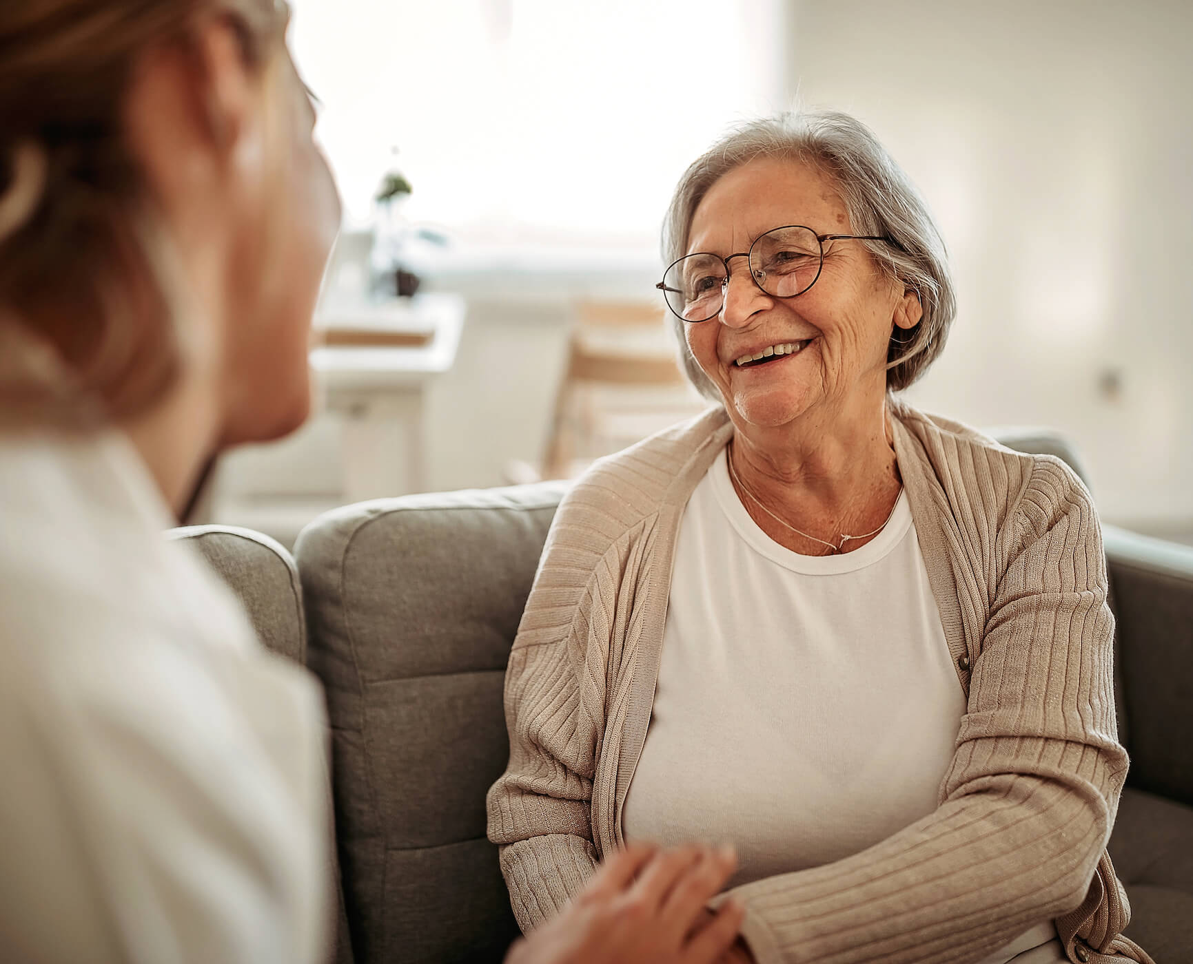 Senior woman sitting on the couch talking to another person